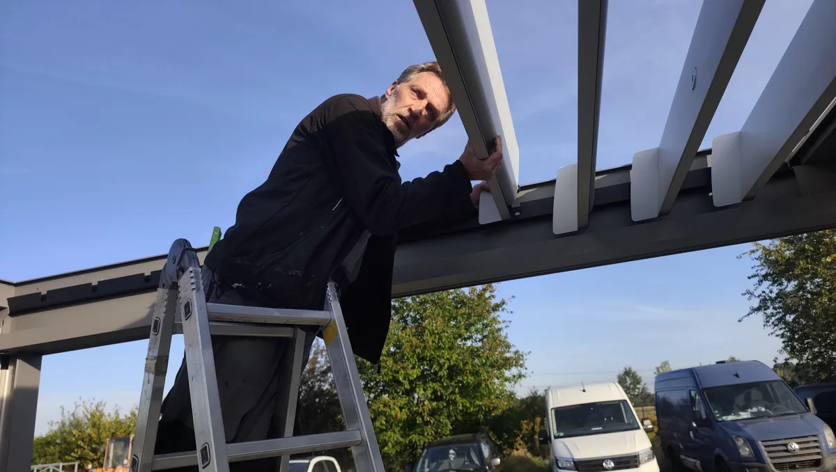 Einsetzen einer Aluminiumlamelle in den Rahmen des Ausstellungsdachs