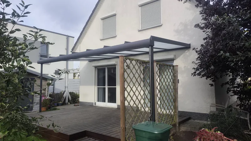 Fertiges Terrassendach mit matter Glaseindeckung und sichtbarem Fallrohr neben der rechten Stütze