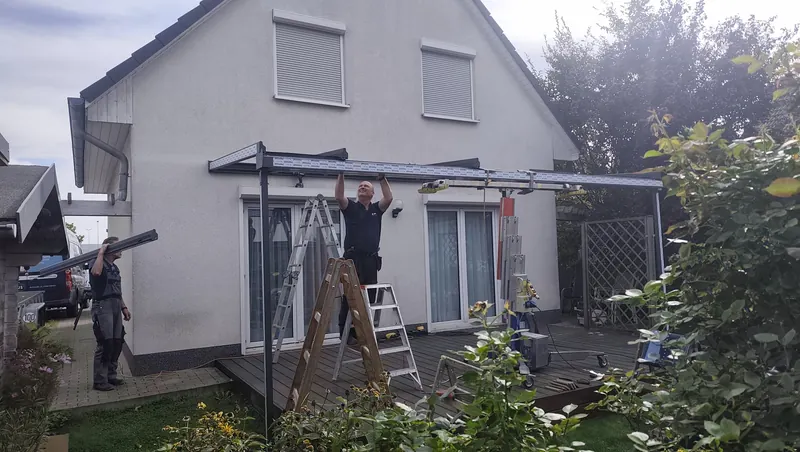 Karalus-Team beim Aufbau der Dachkonstruktion auf zwei Stützen mit Montagehilfe
