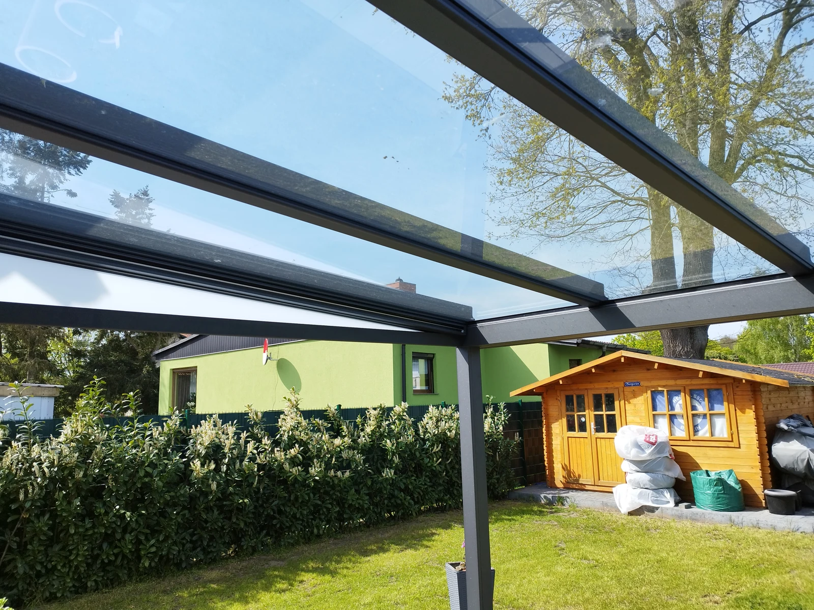 Blick unter ein Aluminium-Glasdach in den Garten