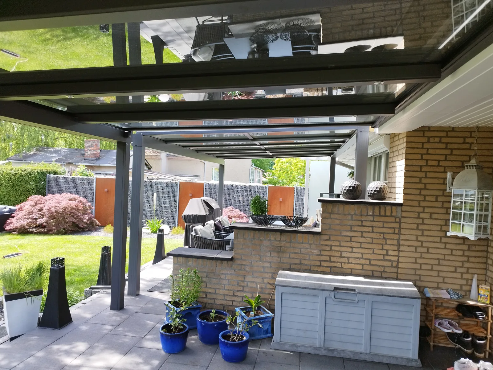 Blick unter ein eigenes klares Glasdach vor einer Klinkerfassade