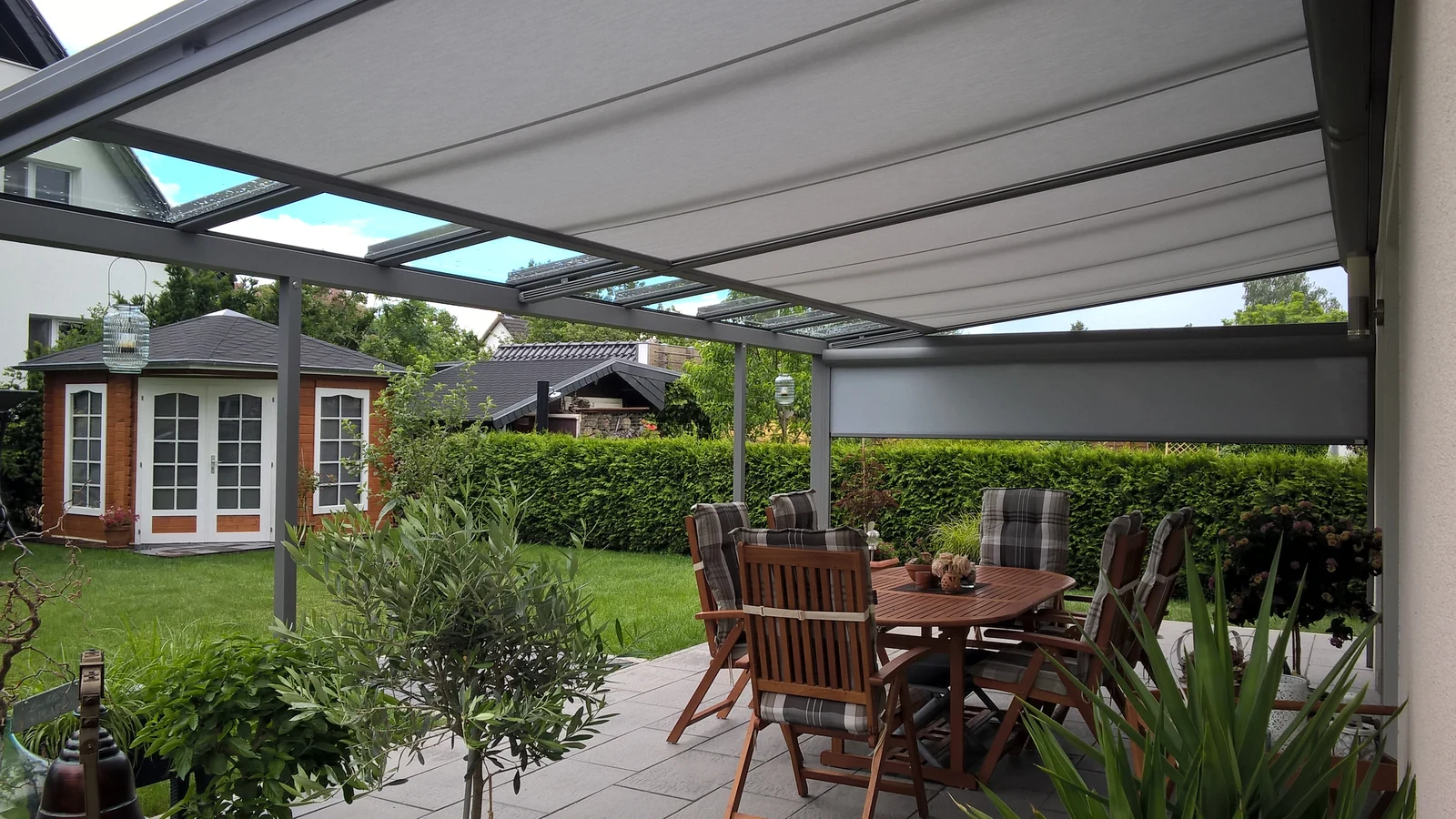 Blick vom Sitzbereich unter einer eigenen Überdachung in den grünen Garten