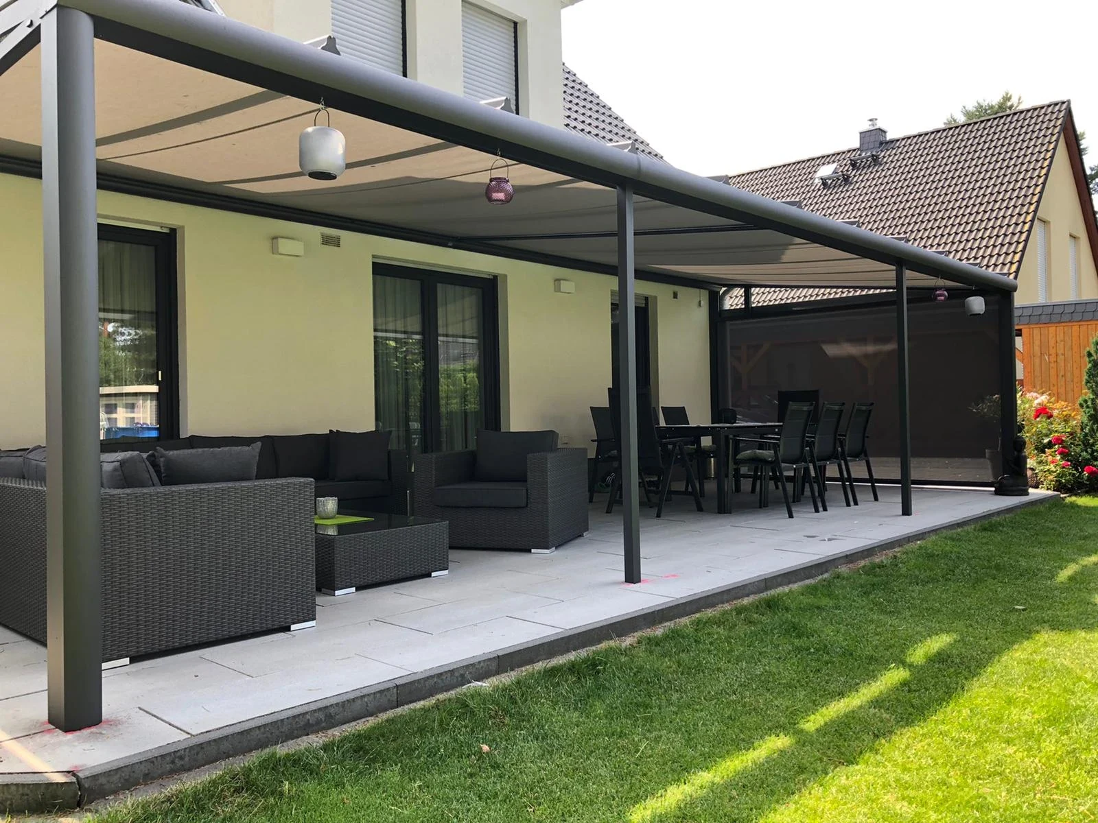 Seitliche Ansicht eines eigenen dunklen Aluminium-Terrassendachs mit Gartenmöbeln in Mahlsdorf
