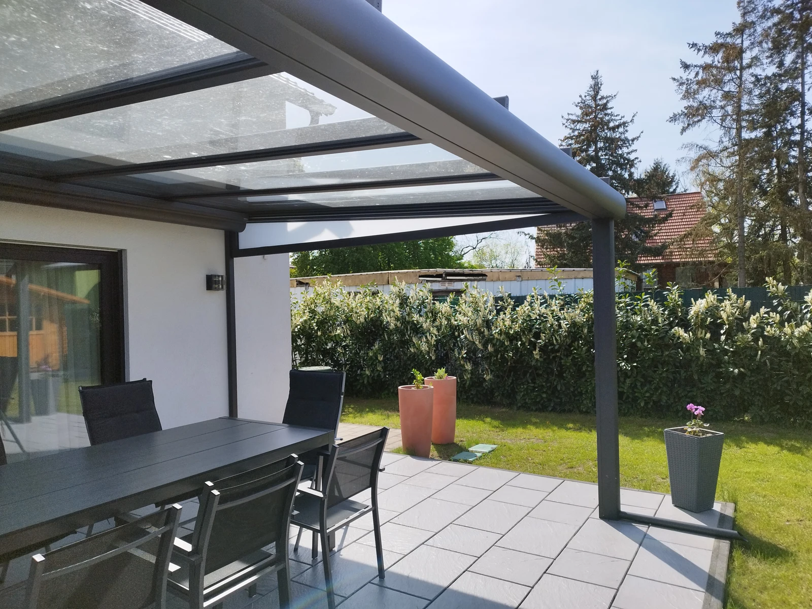 Glasdach von innen mit dunklen Profilen und Blick in den Garten