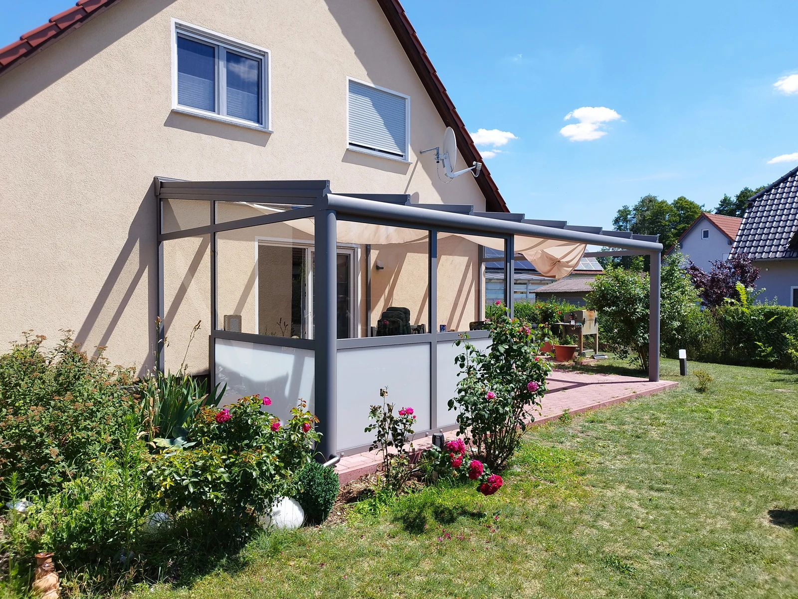 Terrassendach an beiger Hausfassade mit seitlichen Glasfeldern