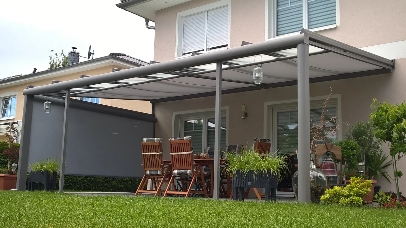 Eigene Terrassenüberdachung mit Esstisch, Gartenstühlen und seitlichem Sonnenschutz