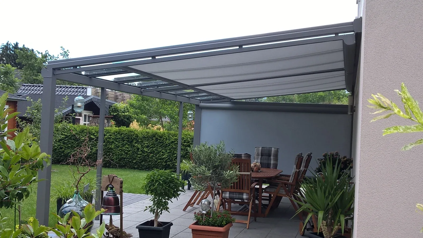 Eigener Sitzbereich unter dem Terrassendach mit Blick entlang der Gartenbepflanzung
