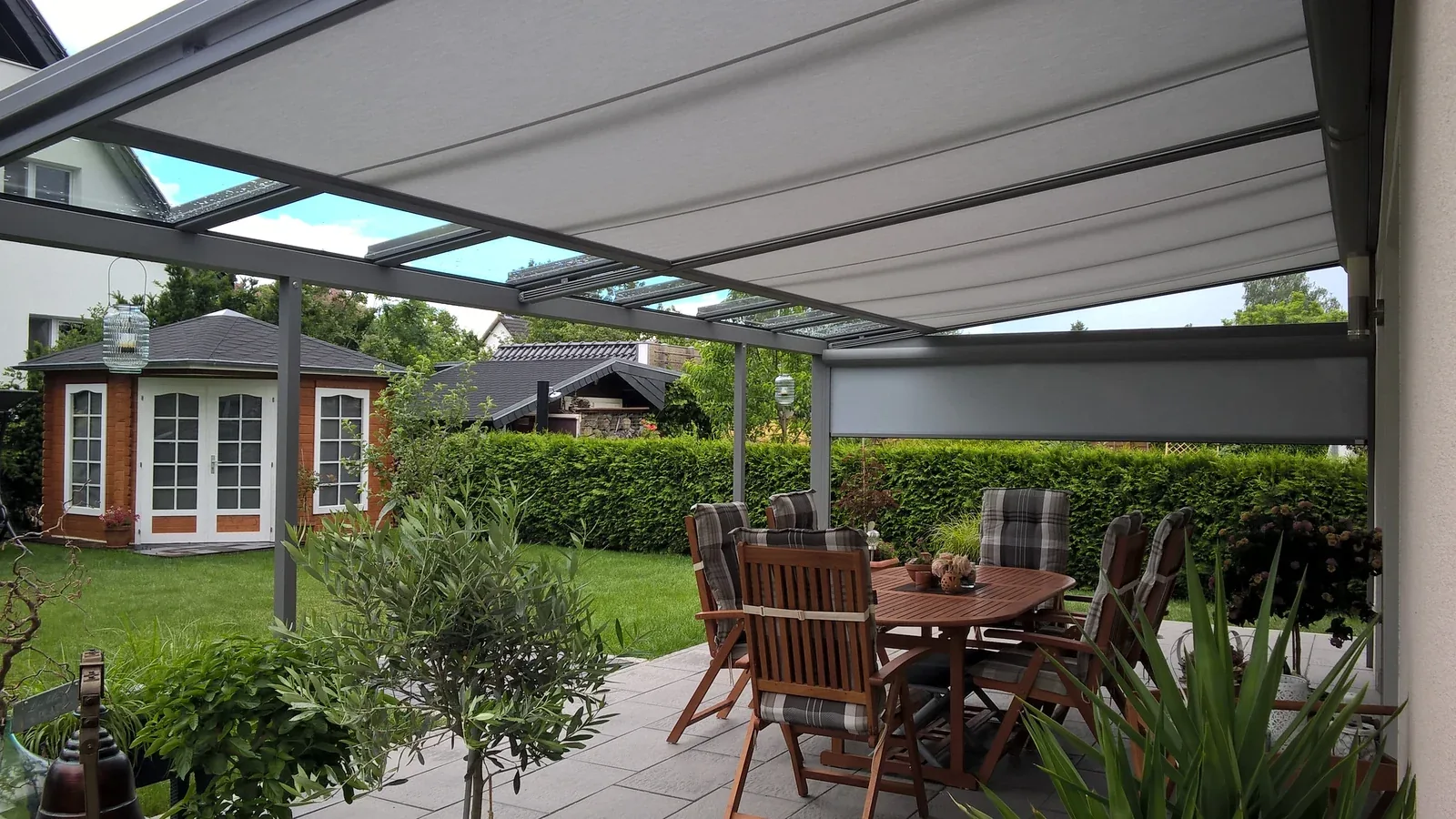 Blick vom Sitzbereich unter einer eigenen Überdachung in den grünen Garten
