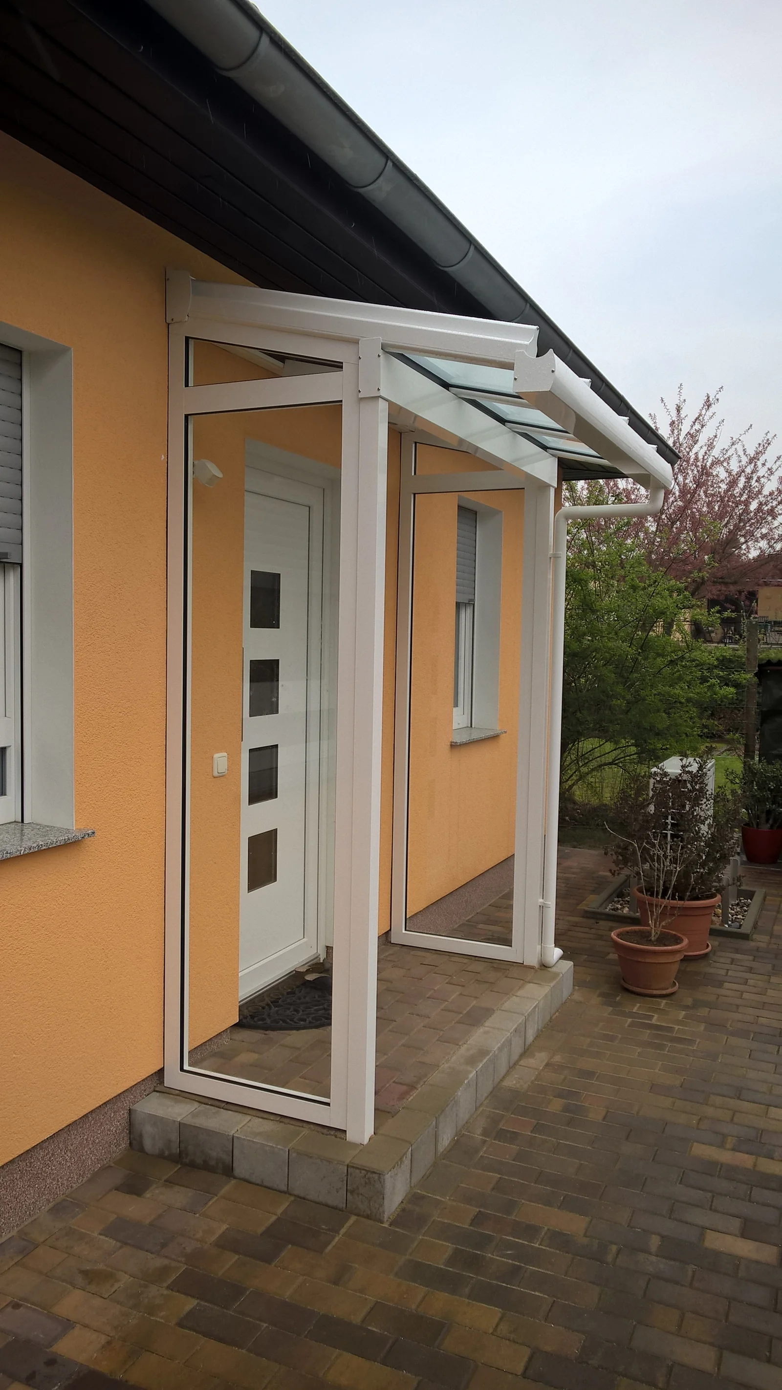 Weiße Eingangsüberdachung mit Klarglasdach und zwei Seitenteilen in Fredersdorf