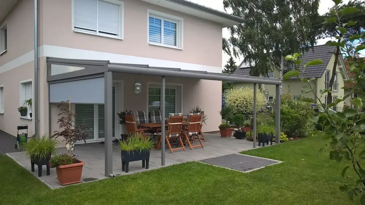 Gartenansicht des Terrassendachs in Birkenstein mit eingefahrenem Sonnenschutz