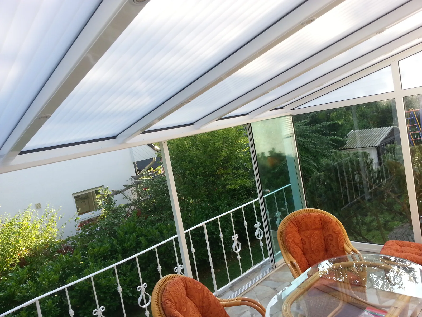 Innenansicht einer weißen Terrassenüberdachung mit Stegplatten und Ganzglas-Schiebeelementen in Berlin-Mahlsdorf