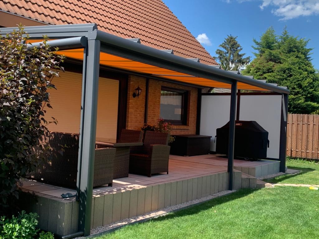 Terrassendach mit ausgefahrener orangefarbener Markise.