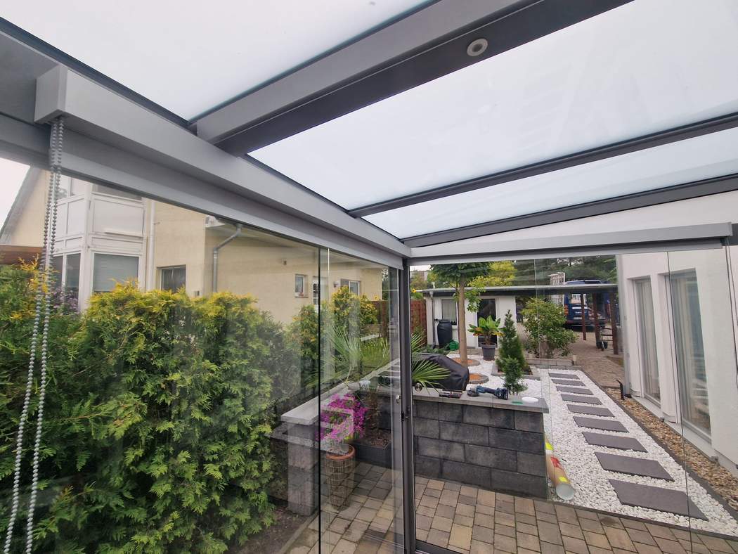 Sitzplatz unter dem Glasdach mit seitlicher Beschattung.