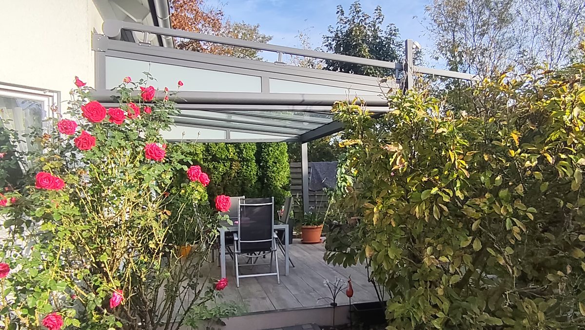 Aufglasmarkise und Terrassendach zwischen den Rosen.