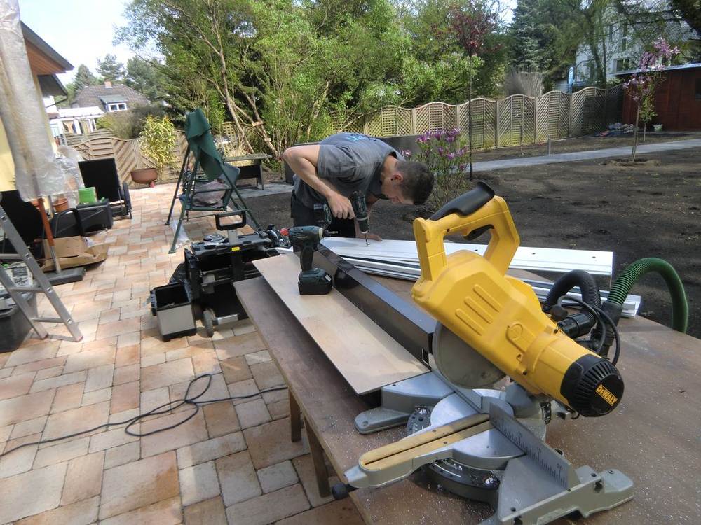 Montage eines Terrassendachs: ein Mitarbeiter bearbeitet ein weißes Aluminiumprofil