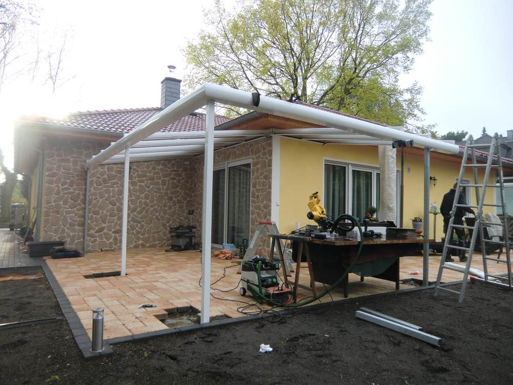 Terrassendach über Eck im Aufbau mit weißen Stützen und montierten Dachprofilen