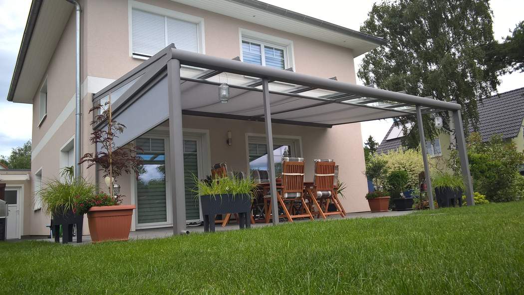 Blick vom Garten auf den Sitzplatz unter dem Dach.
