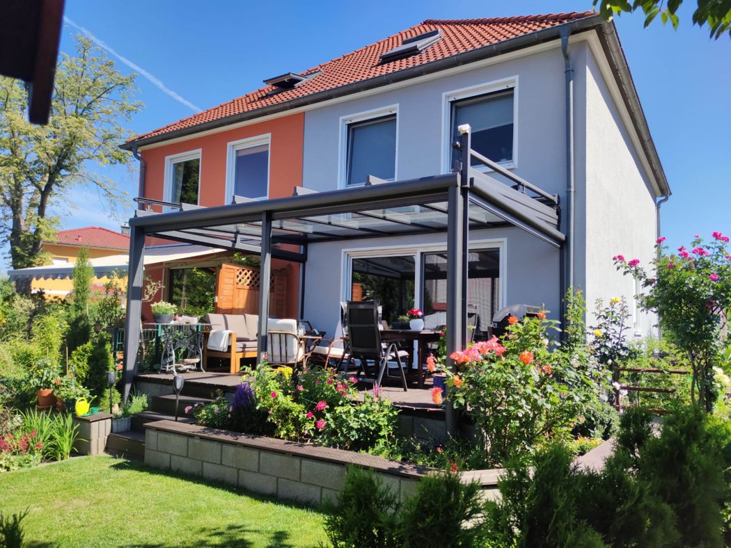 Das offene Glasdach an der zweifarbigen Hausfassade.