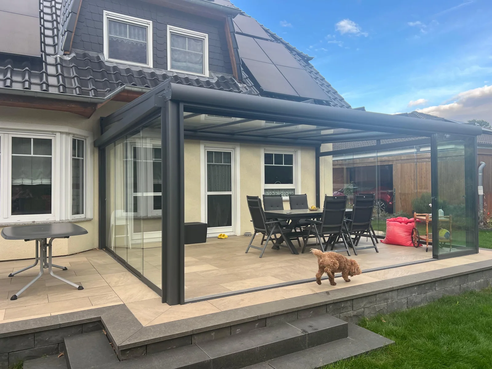 Sommergarten an der Hausfassade mit dem Hund im Garten