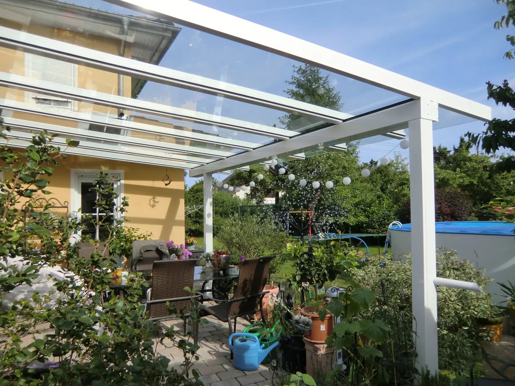 Weißes Terrassendach mit vorderem Glasüberstand am Haus im Toskana-Stil.