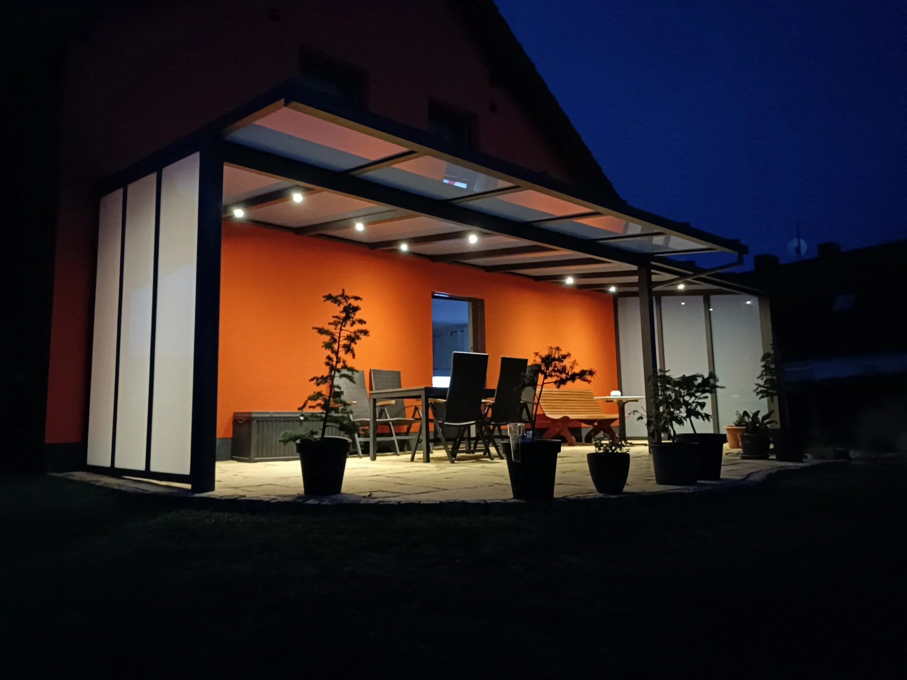 Abendansicht des Terrassendachs in Vogelsdorf mit eingeschalteter Sparrenbeleuchtung.