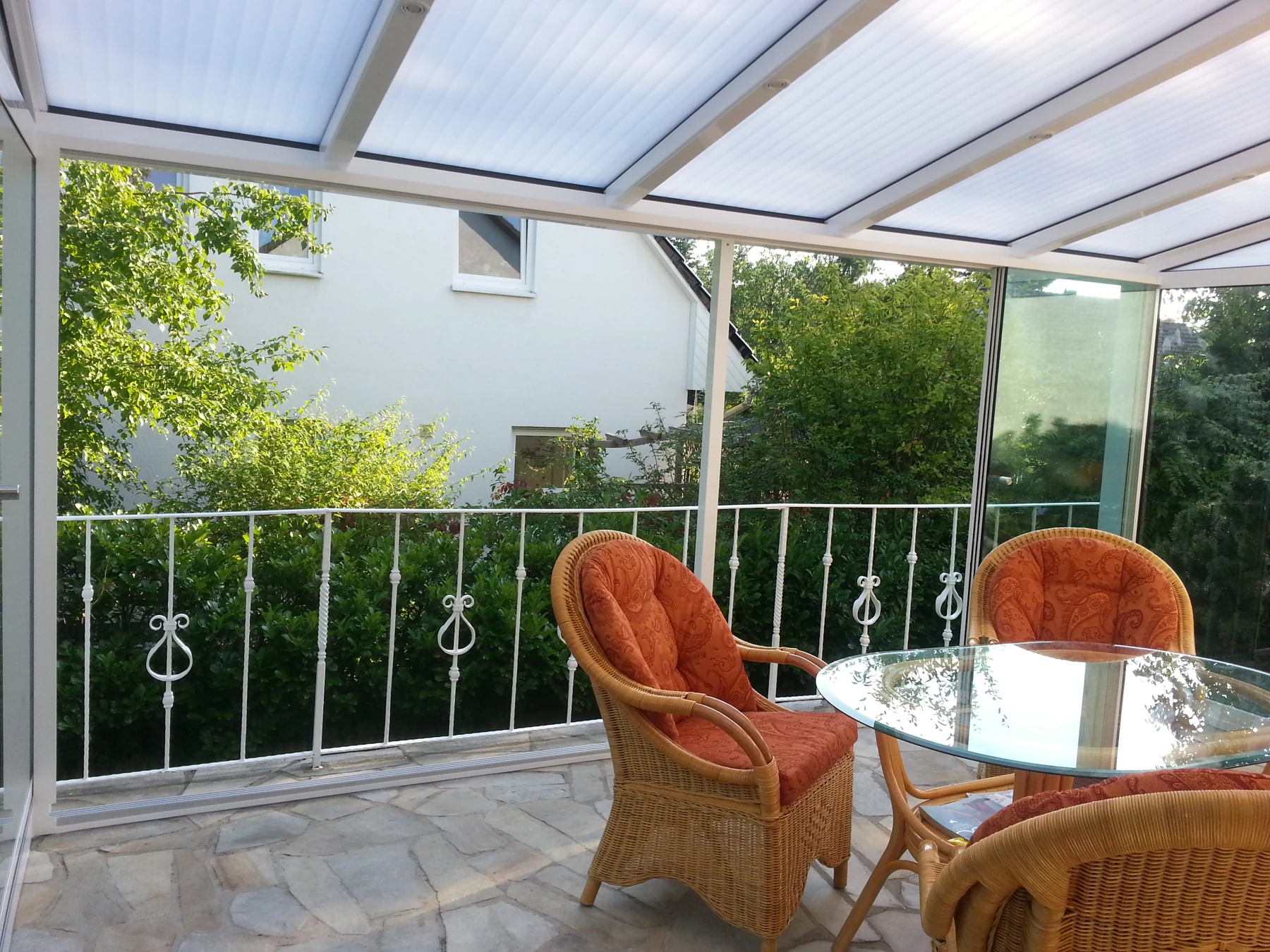 Heller Sitzbereich unter der weißen Terrassenüberdachung.