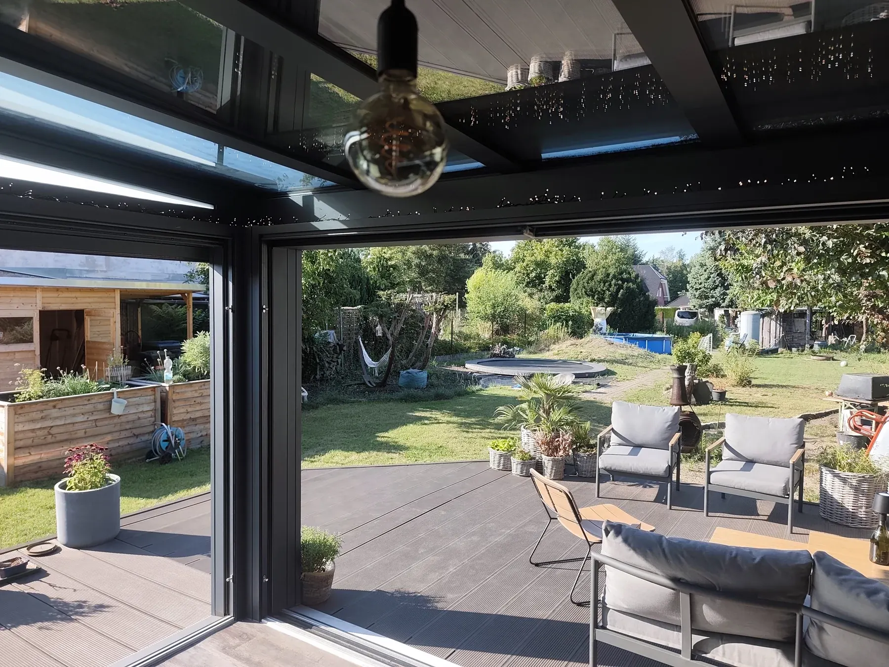 Innenansicht mit Dachverglasung und geöffnetem Zugang zum Garten.