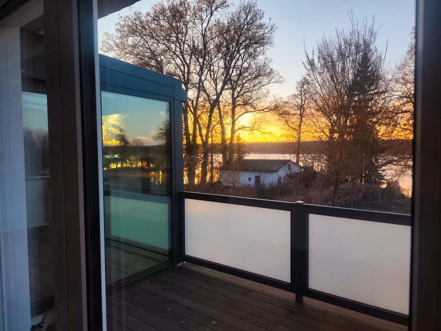 Blick durch die geöffnete Schiebeanlage auf den Balkon und den Abendhimmel.